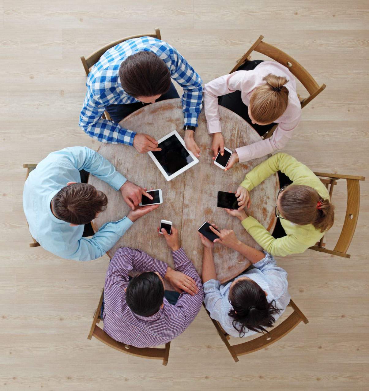 people sitting around a round table with devices